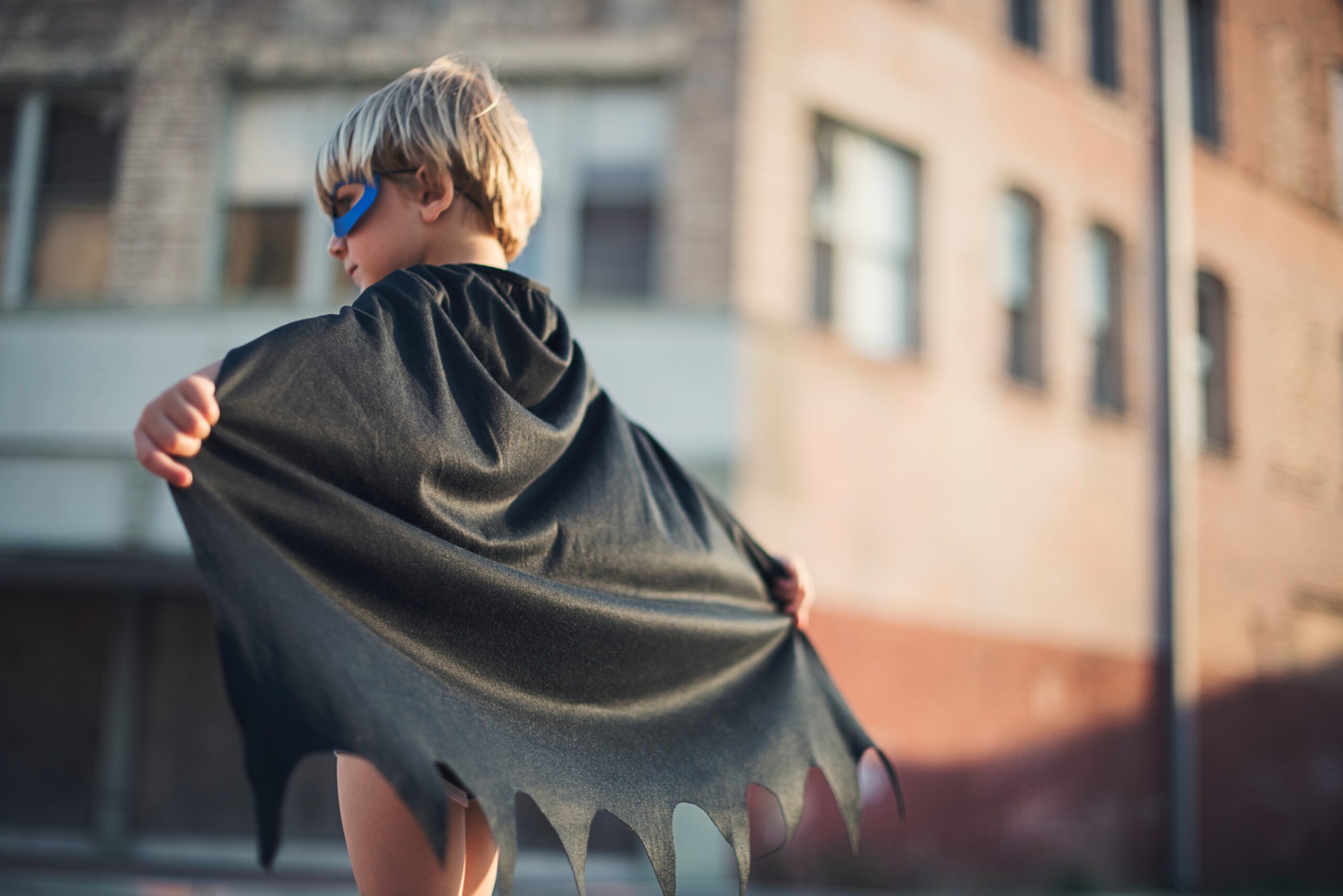 Child with cape and mask stands on street exemplifying a super hero_ offering the same ideals as Your Agency Works