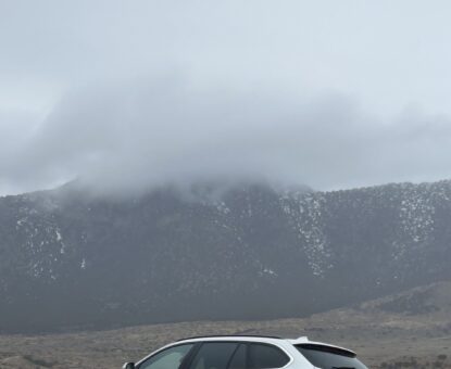 Monaya M. MaGaurn, lifestyle physicist with Agency World Resources WTR White BMW 328 D wagon in front of mountain range on cloudy day